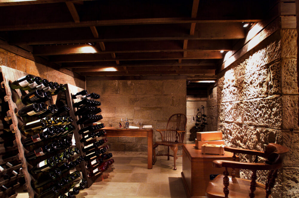 Expansive Wine Cellar with sandstone block walls below the floor of a house